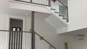 Een meerlaags interieur met een trap, een kroonluchter en een eetgedeelte met een marmeren tafel.