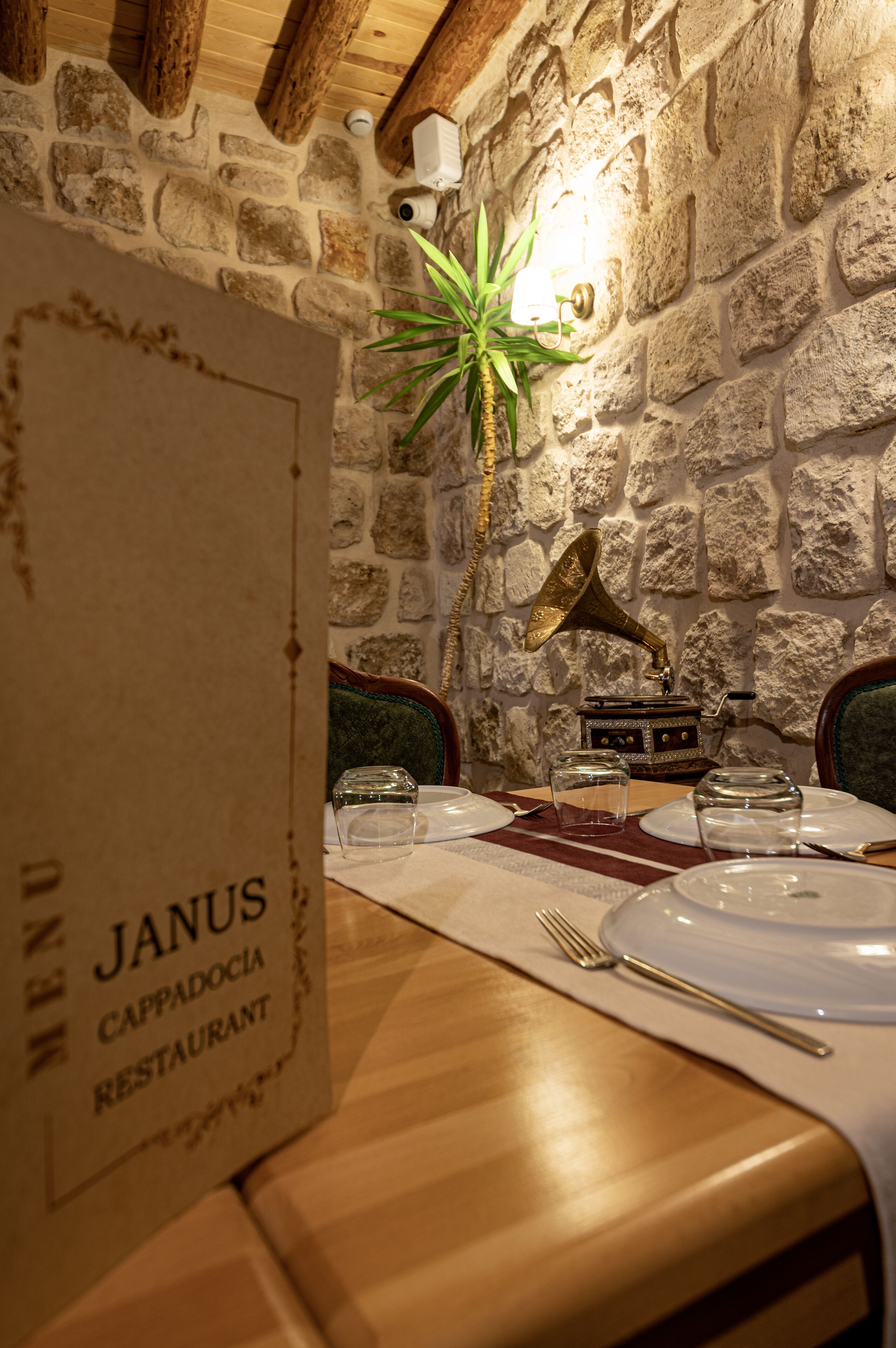 Ein Restaurant mit einer Steinwand, Holzbalkendecke und einem Menüständer.
