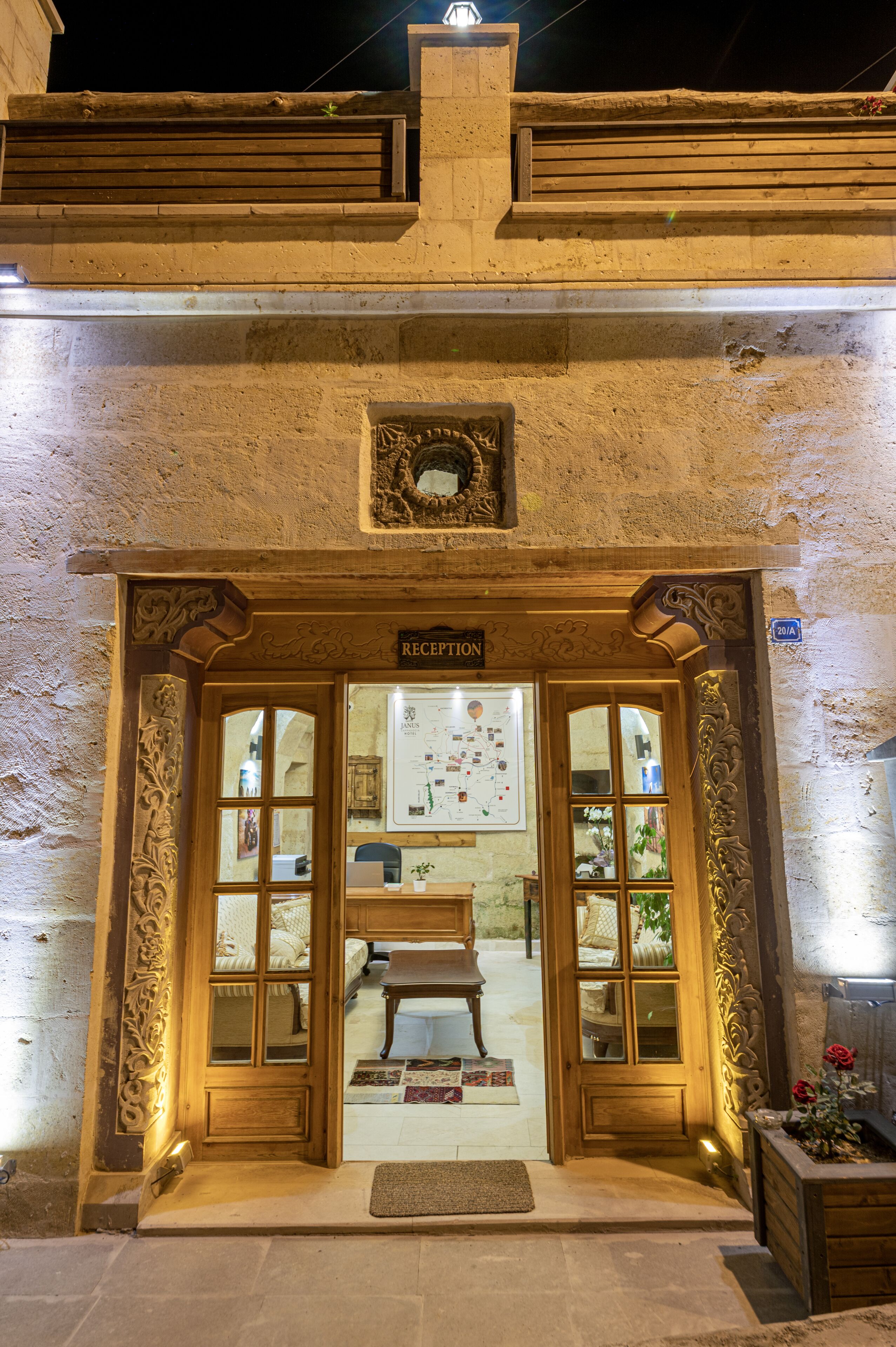 Zona de recepción con puerta de madera, mostrador de recepción y pared con un cuadro enmarcado.