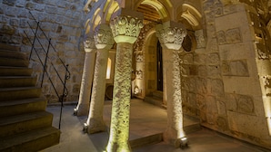 A stone building with a staircase leading to an upper level, featuring ornate columns and a wooden ceiling. - Janus Cappadocia Hotel (Ürgüp)