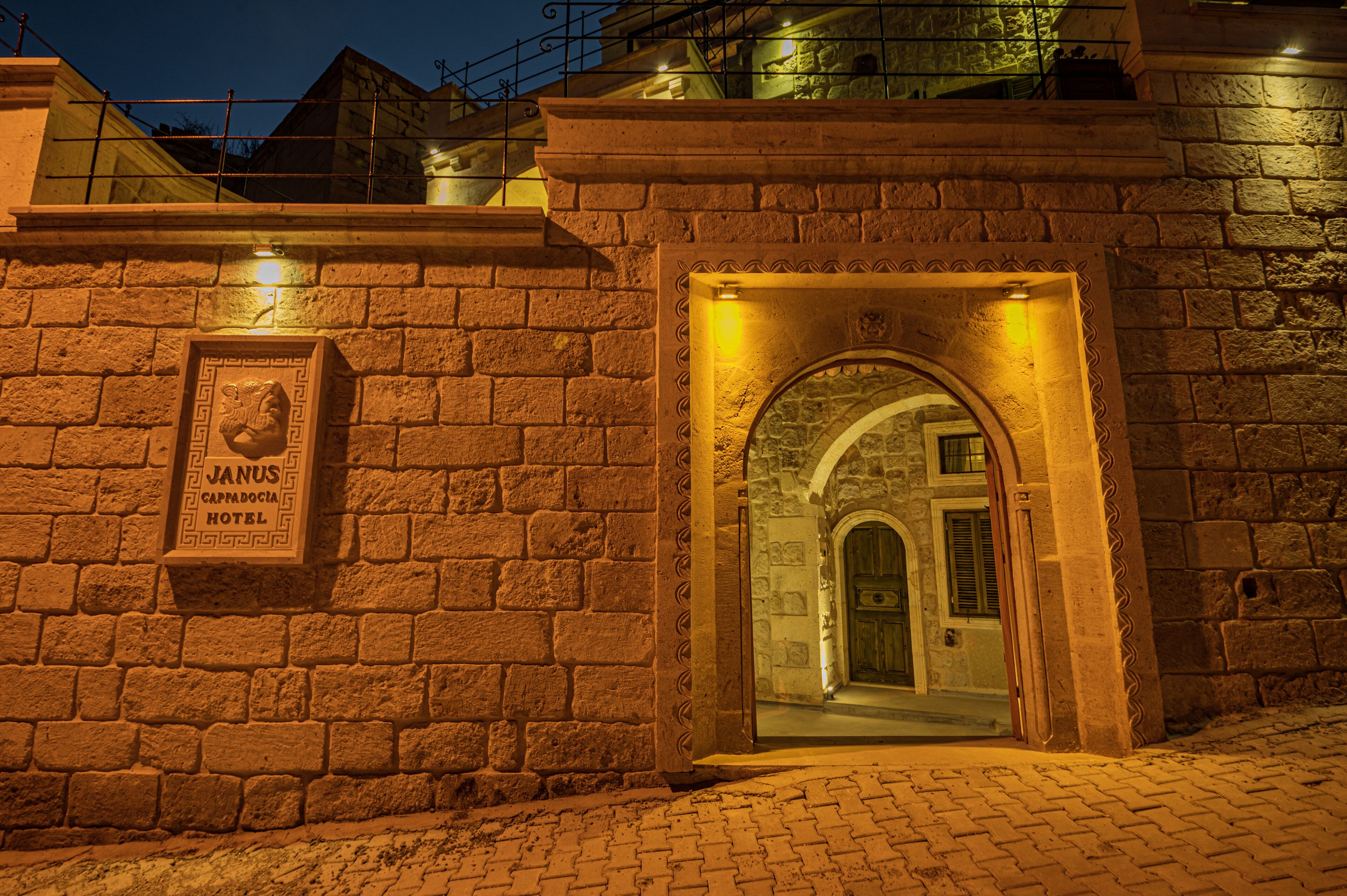 A stone wall with a sign for Janus Capodoccia Hotel.