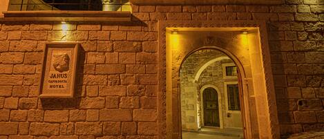 A stone wall with a sign for Janus Capodoccia Hotel.