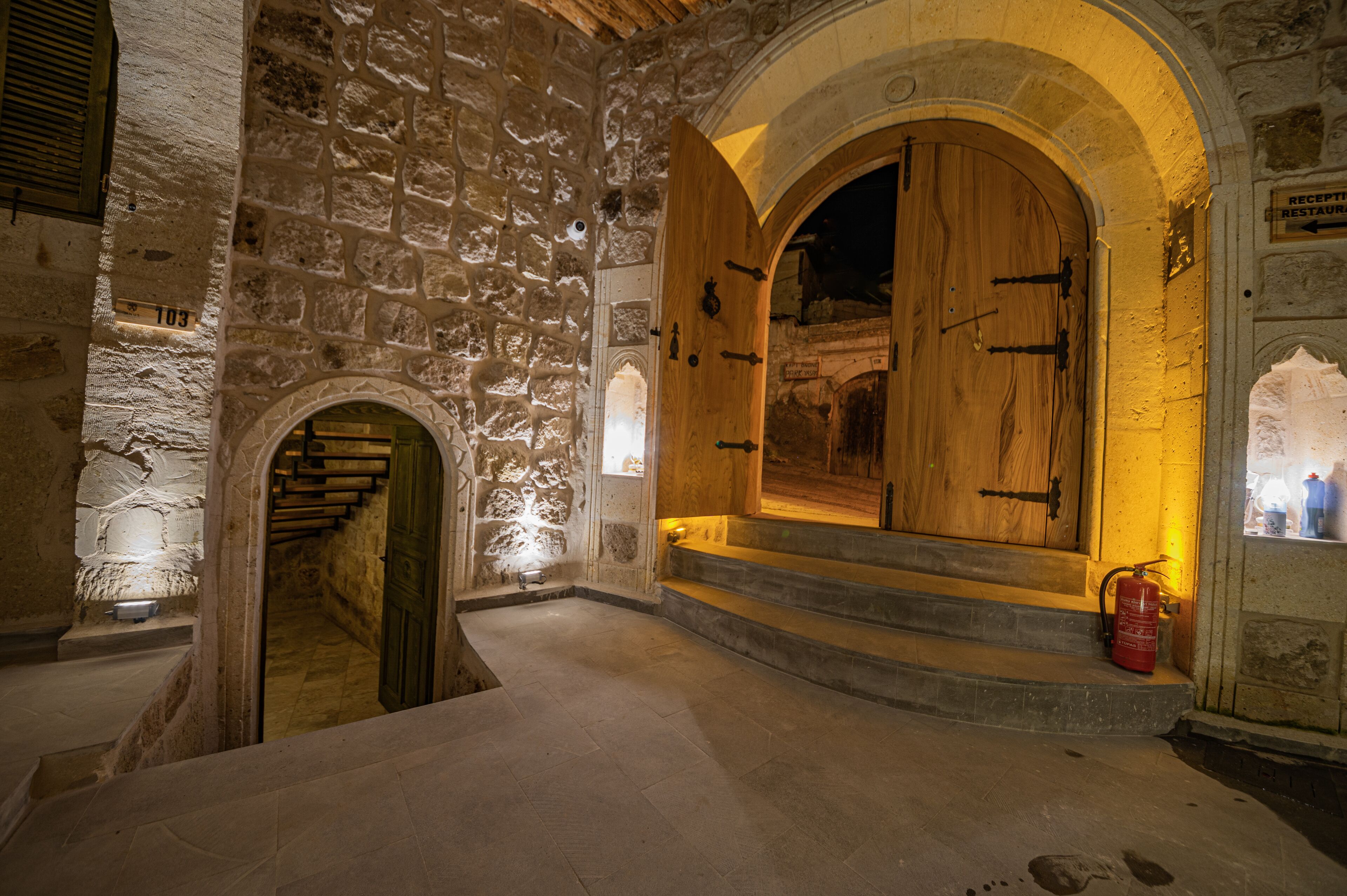 A stone-walled interior with a wooden door and steps leading to a higher level.