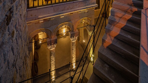 A stone building with an arched entrance and a staircase leading to an upper level. - Janus Cappadocia Hotel (Ürgüp)