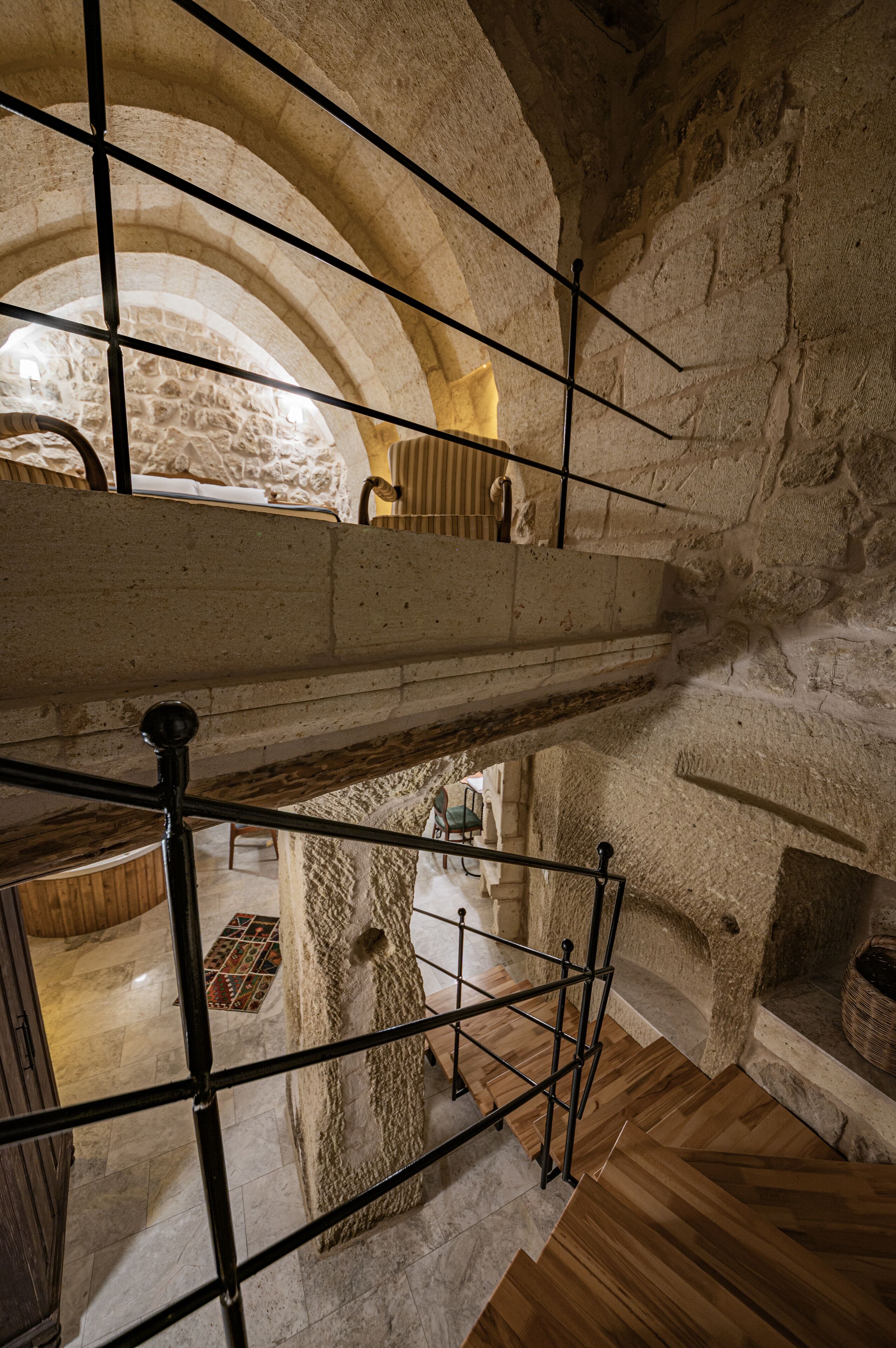 A multi-level stone interior with wooden flooring and metal railings.