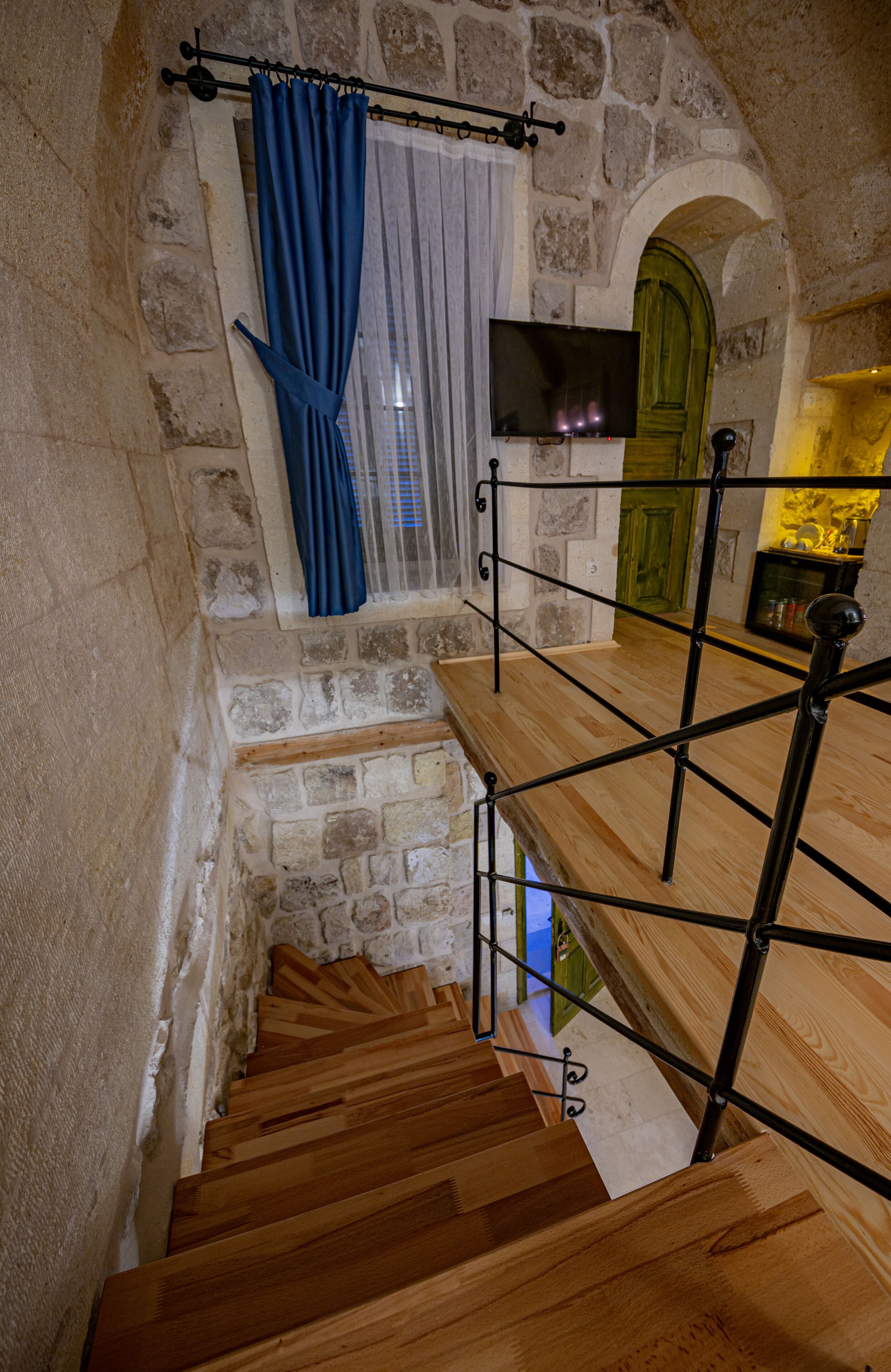 A wooden staircase with stone walls and a green door.