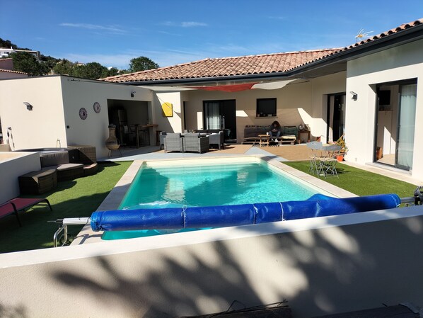 A modern house with a swimming pool, outdoor furniture, and a patio area.