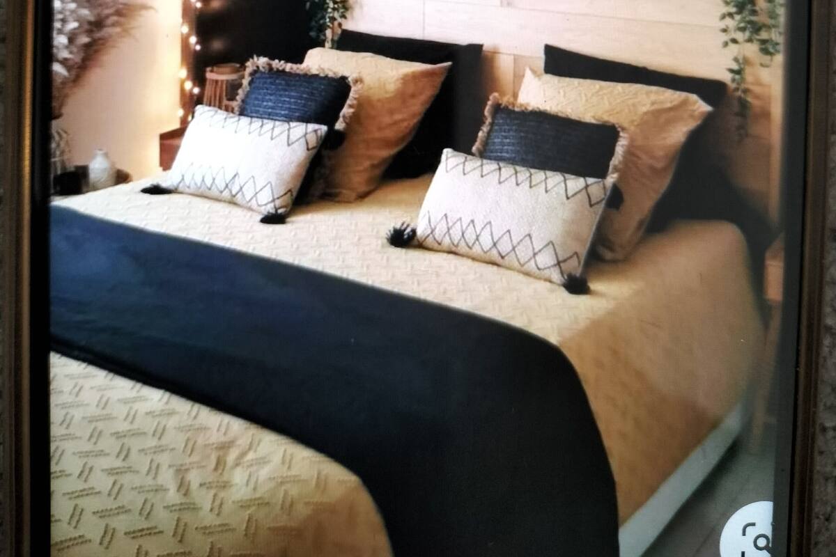 A bedroom with a bed, headboard, wall decorations, and a hanging light fixture.