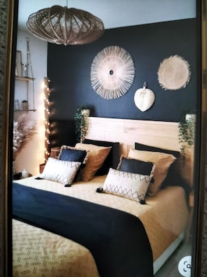 Un dormitorio con cama, cabecero, adornos en la pared y una lámpara colgante.