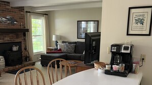 A cozy living room with a fireplace, a television, and a coffee station. - Sunrise Side Retreat - Sleeps 7 (Harrisville)