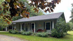 A two-story house with a porch, a garage, and a well-maintained lawn. - Sunrise Side Retreat - Sleeps 7 (Harrisville)