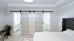 Ein Schlafzimmer mit Bett, Nachttisch, Lampe, Blumentopf und einer Schiebetür zum Kleiderschrank.