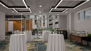 Une salle de conférence avec des tables rondes, des nappes blanches et un tapis à motifs.