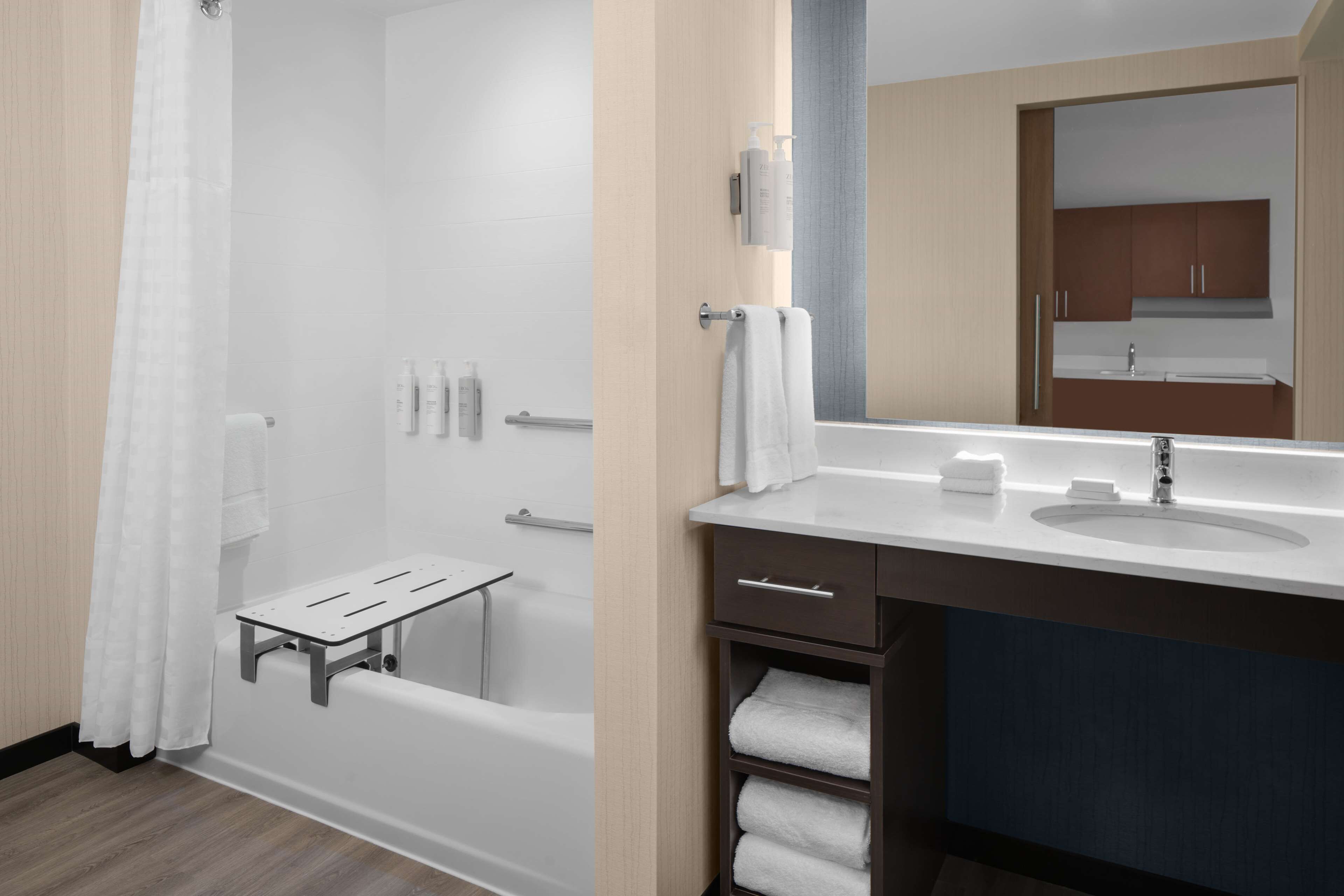 A modern bathroom with a bathtub, a vanity with a sink, and a mirror.