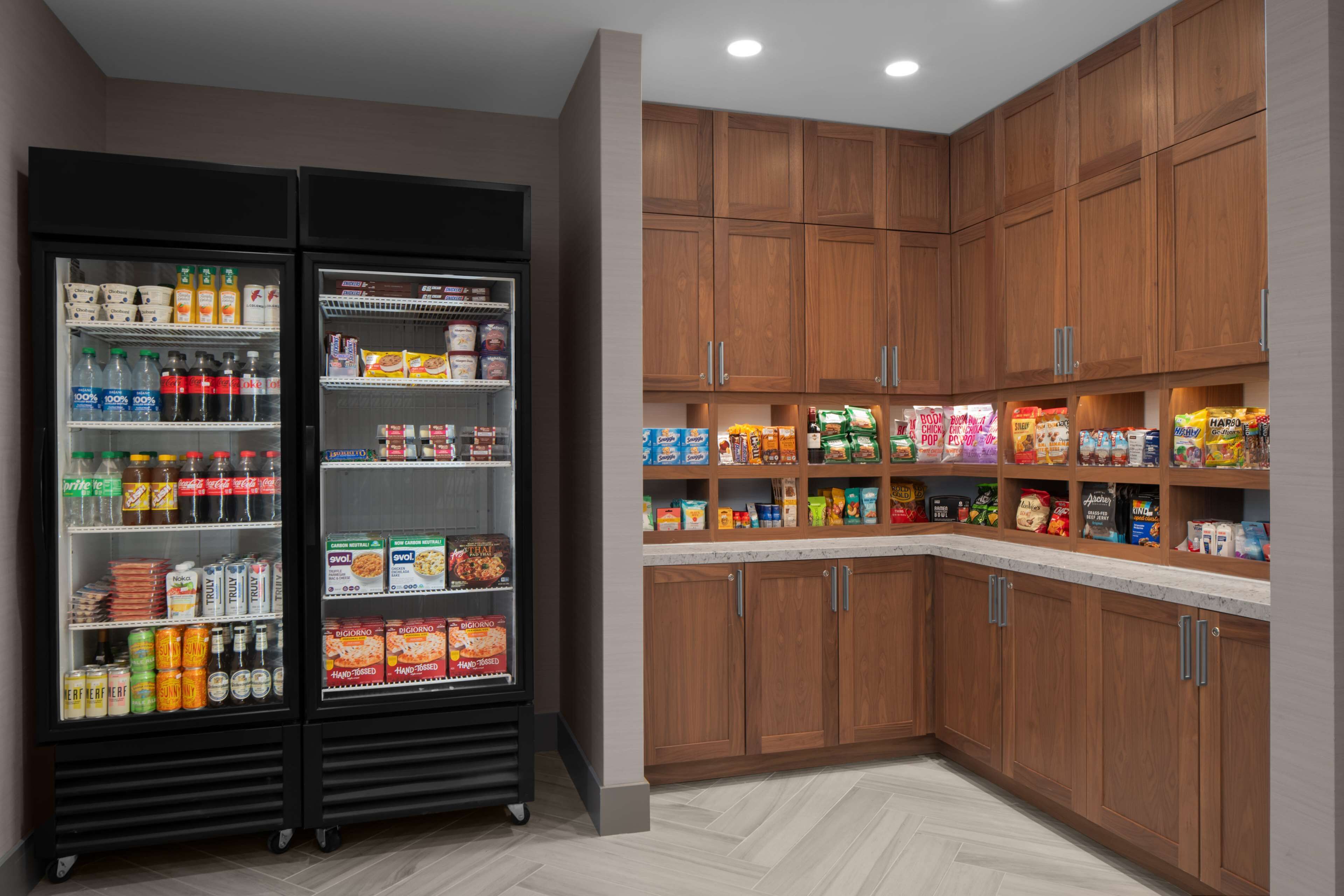 A kitchen with wooden cabinets and a refrigerator stocked with beverages and snacks.