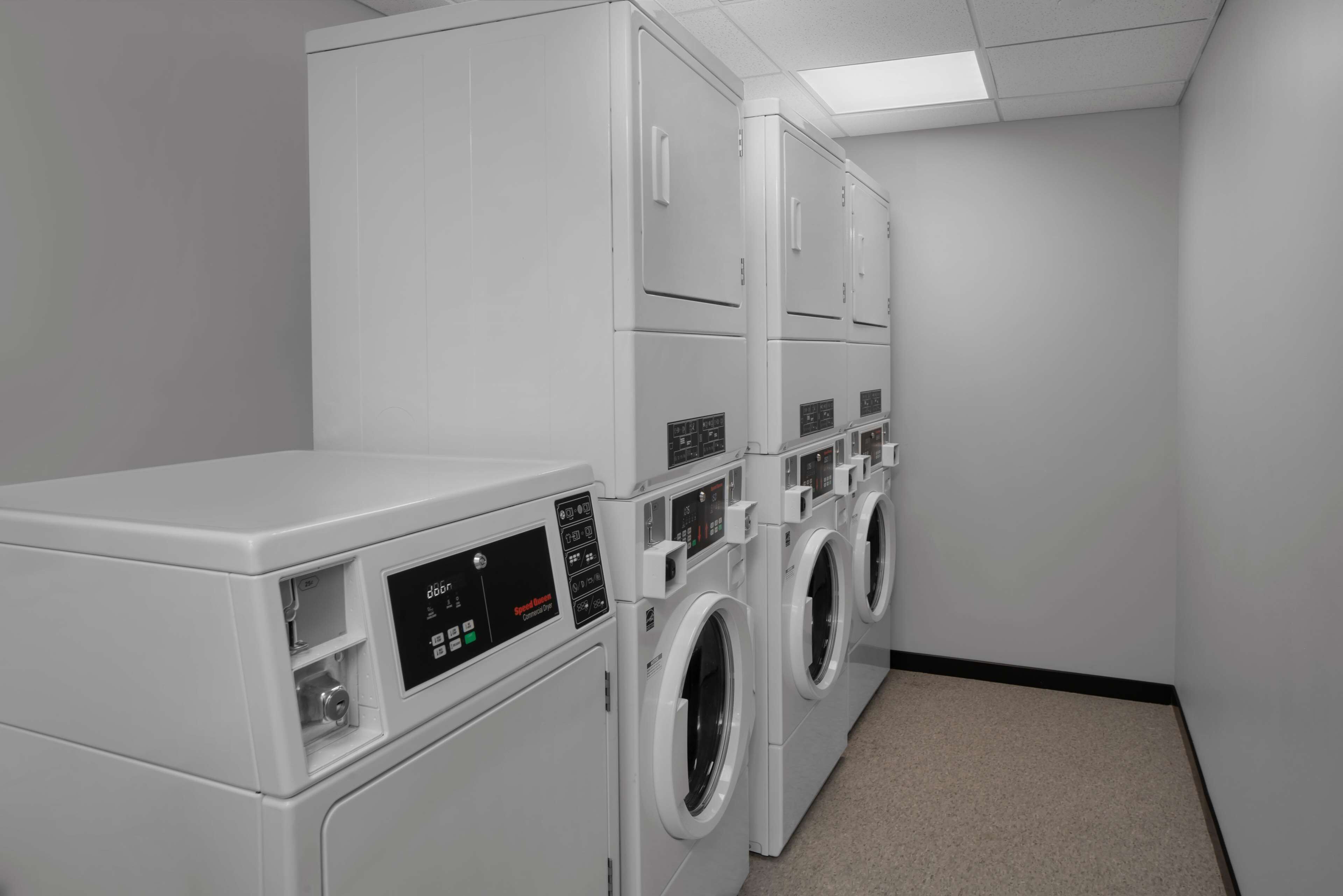 A laundry room with multiple white washing machines and dryers, arranged in a row.