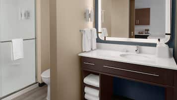 Une salle de bain moderne avec une douche à parois de verre, des toilettes blanches, un meuble-lavabo avec un évier et un porte-serviettes, et un grand miroir.