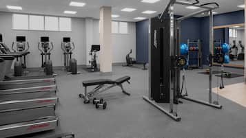 A gym with treadmills, elliptical machines, a bench, and weightlifting equipment.