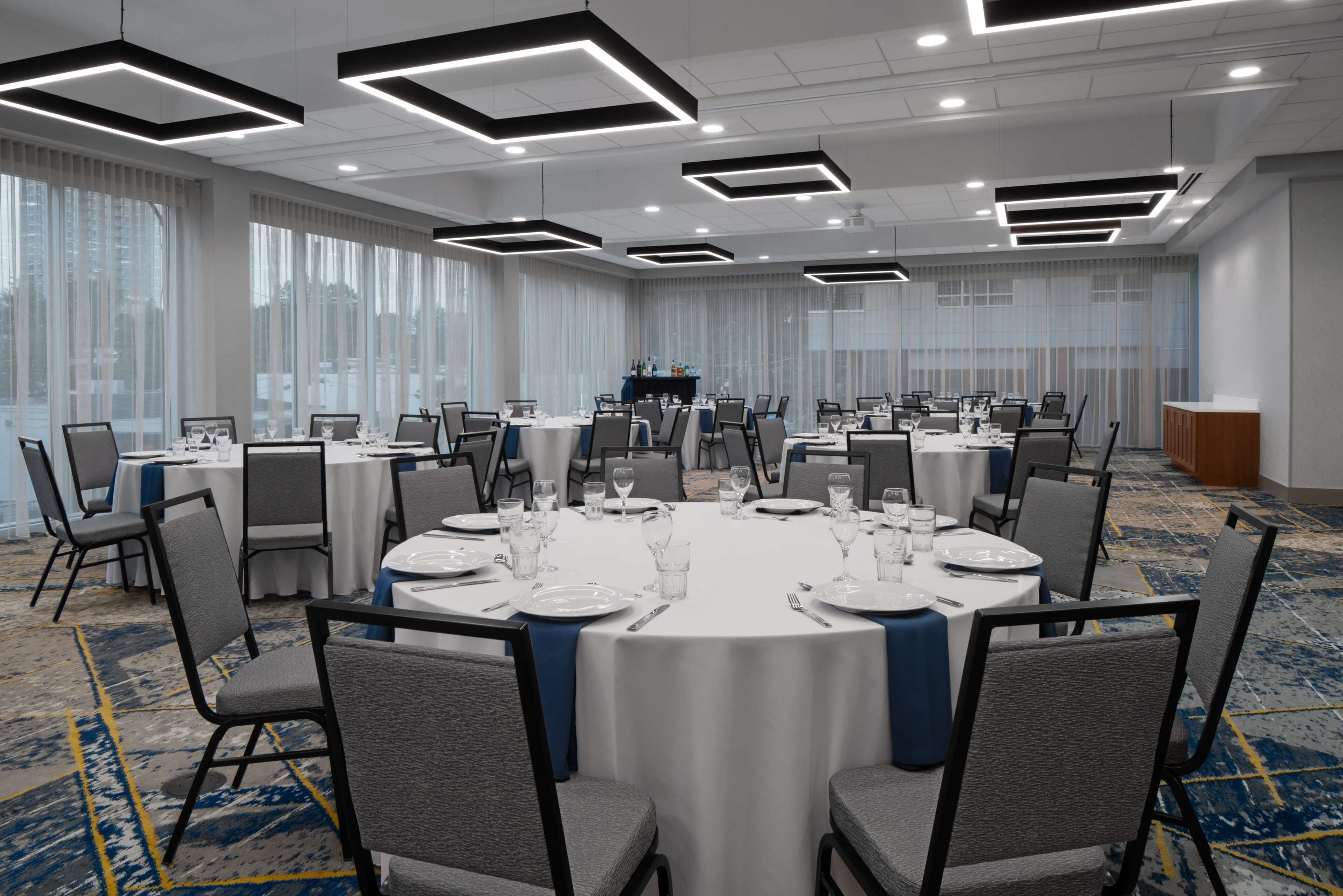 A conference room with round tables, chairs, and a buffet area.