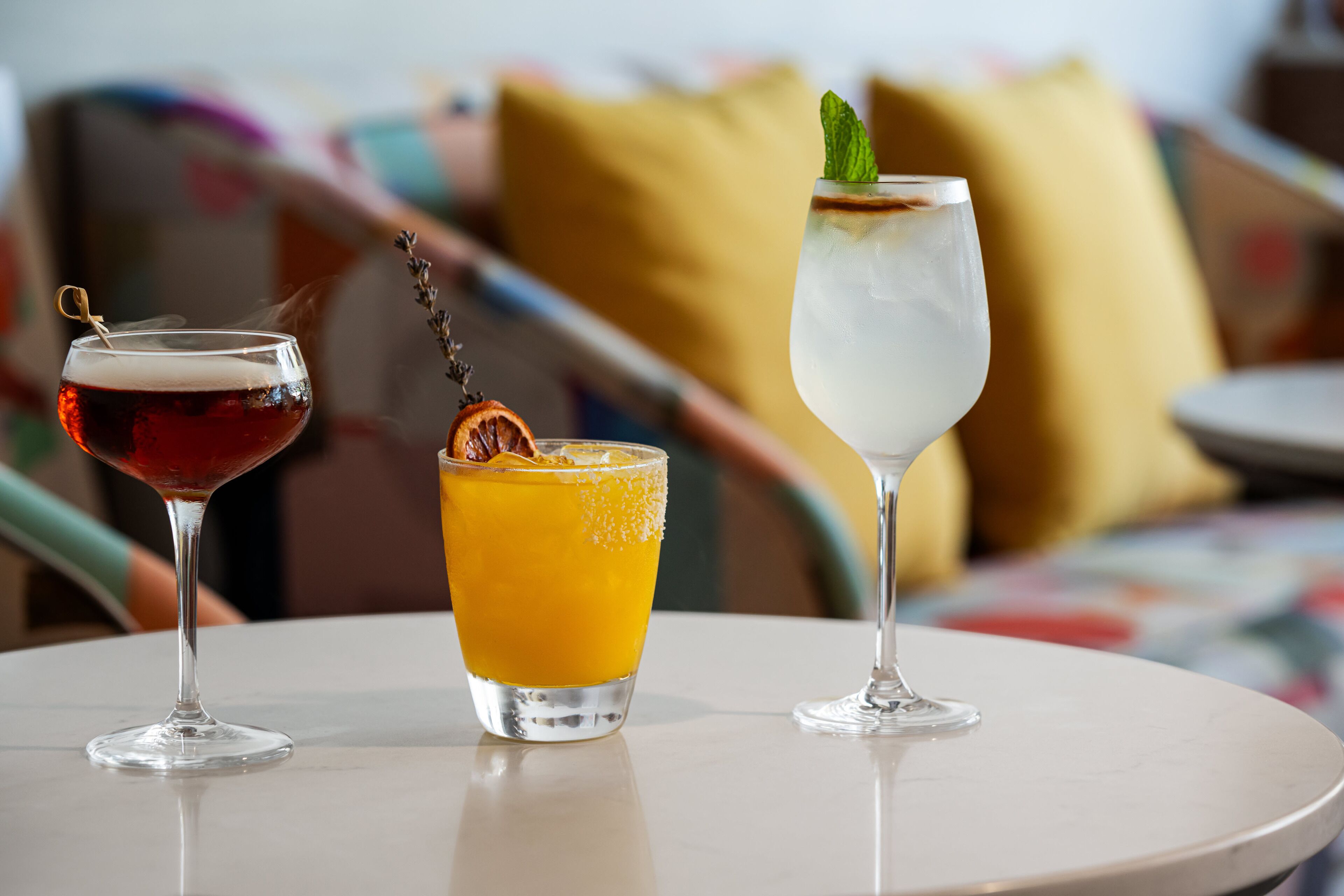 Three glasses of different beverages on a round table.