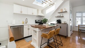 A modern kitchen with white cabinetry, a wooden island, and a skylight.