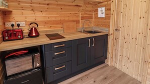 Eine kleine Küche mit Holzwänden, einem Spülbecken, einem Toaster und einem Wasserkocher.