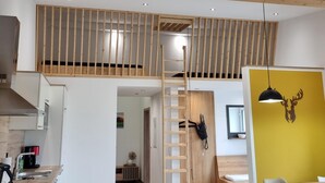 Una cocina moderna con estufa integrada, un comedor con mesa de madera y una pared de acento amarilla.