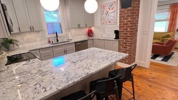 A modern kitchen with a large island, bar stools, and a brick accent wall. - Millhouse in Downtown Jefferson (Jefferson)