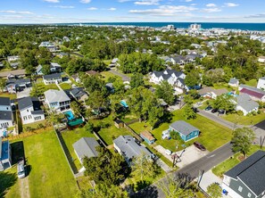 An aerial view of a residential area with houses, green lawns, and a clear view of the ocean. - Quiet Hideaway Half a Mile to the Beach a Mile to the Boardwalk
Linens Included! (Carolina Beach)