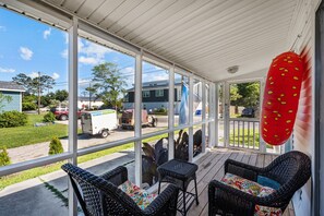 A covered porch with wicker furniture and a red punching bag.