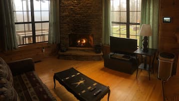 Cozy living room with a fireplace, comfortable seating area, and large windows.