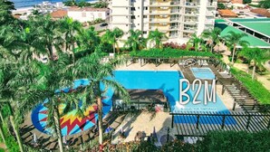 A multi-story hotel with a pool area, surrounded by palm trees and a view of the sea. - Beto Carrero, Vista Espetacular do Mar, Home Club (Penha)