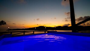 A swimming pool with a sunset view, a bridge, and a distant mountain range.