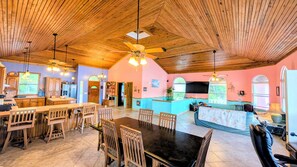A spacious kitchen with wooden cabinets, a dining area with a large table and chairs, and a bar area with a counter and seating.