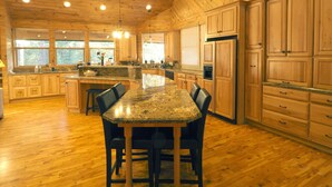 Una cocina amplia con armarios de madera, encimeras de granito y una isla central con taburetes de bar.