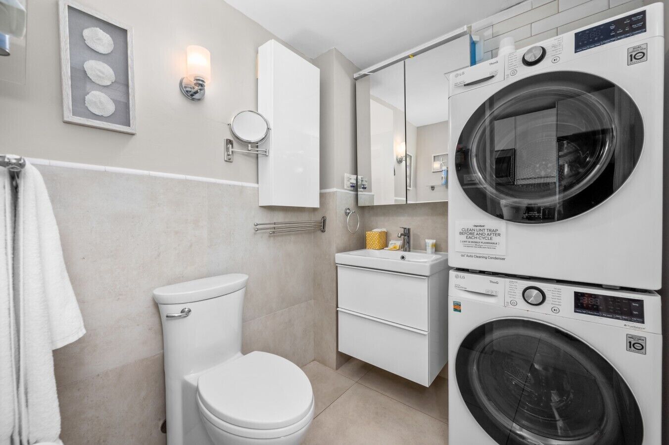 Un baño moderno con inodoro, lavabo y lavadoras apiladas.