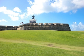 A historic fort with a prominent tower, surrounded by a grassy area and a clear sky. - Boutique Lagoon Retreat · Condado (San Juan)