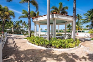 A covered outdoor area with a pool, palm trees, and lounge chairs. - Boutique Lagoon Retreat · Condado (San Juan)