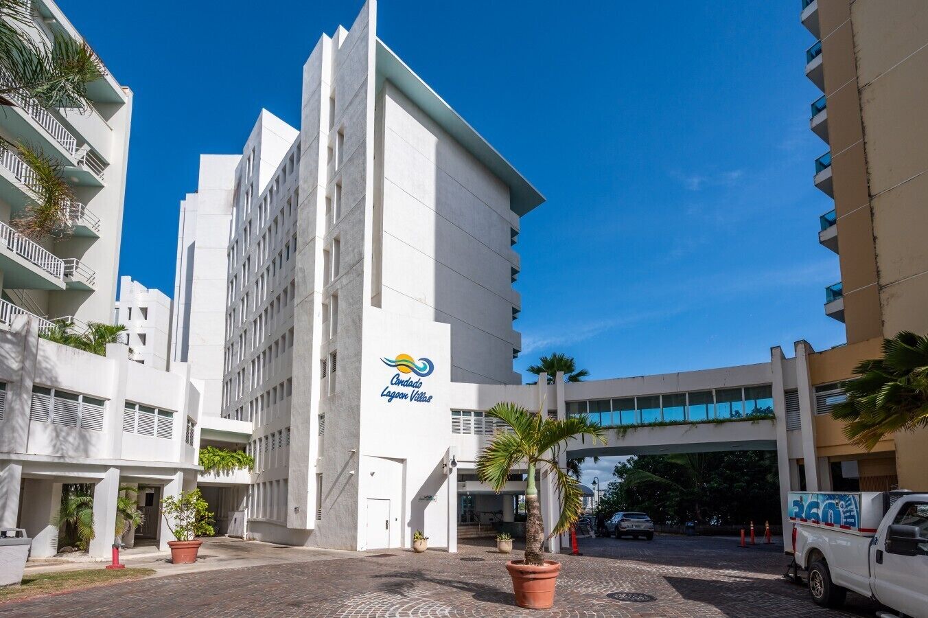 A modern hotel with a prominent logo, a central staircase, and a paved entrance area.