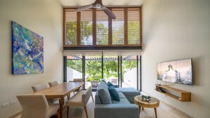 A modern living room with a dining area, a sofa, a TV, and artwork on the walls. - Awa 107 At AWA Residences - Playacar ll (Playa del Carmen)