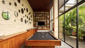 A pool table in a modern room with a wooden cabinet and shelves with decorative items. - Awa 107 At AWA Residences - Playacar ll (Playa del Carmen)