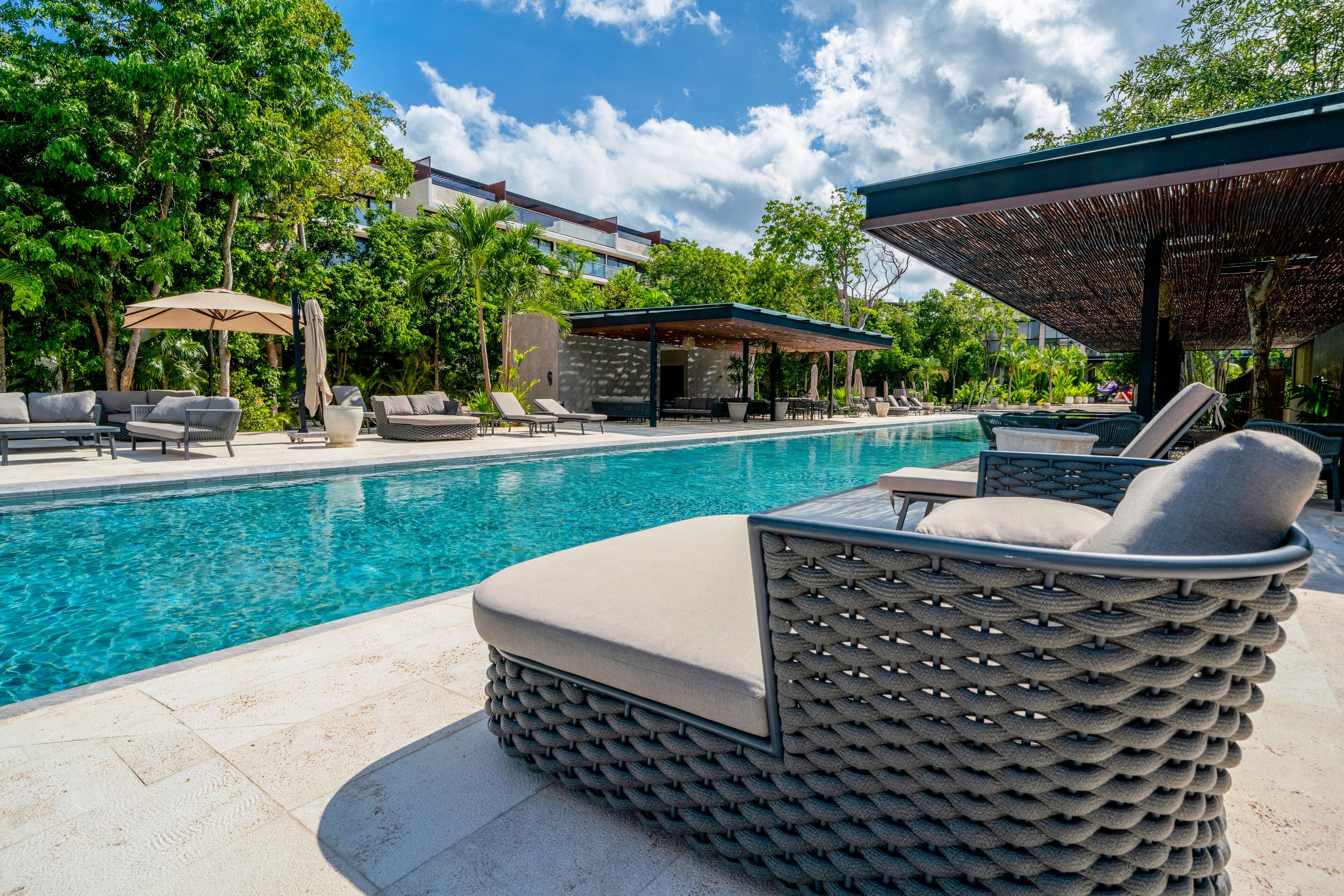 A pool area with lounge chairs, a covered seating area, and a stone building in the background.