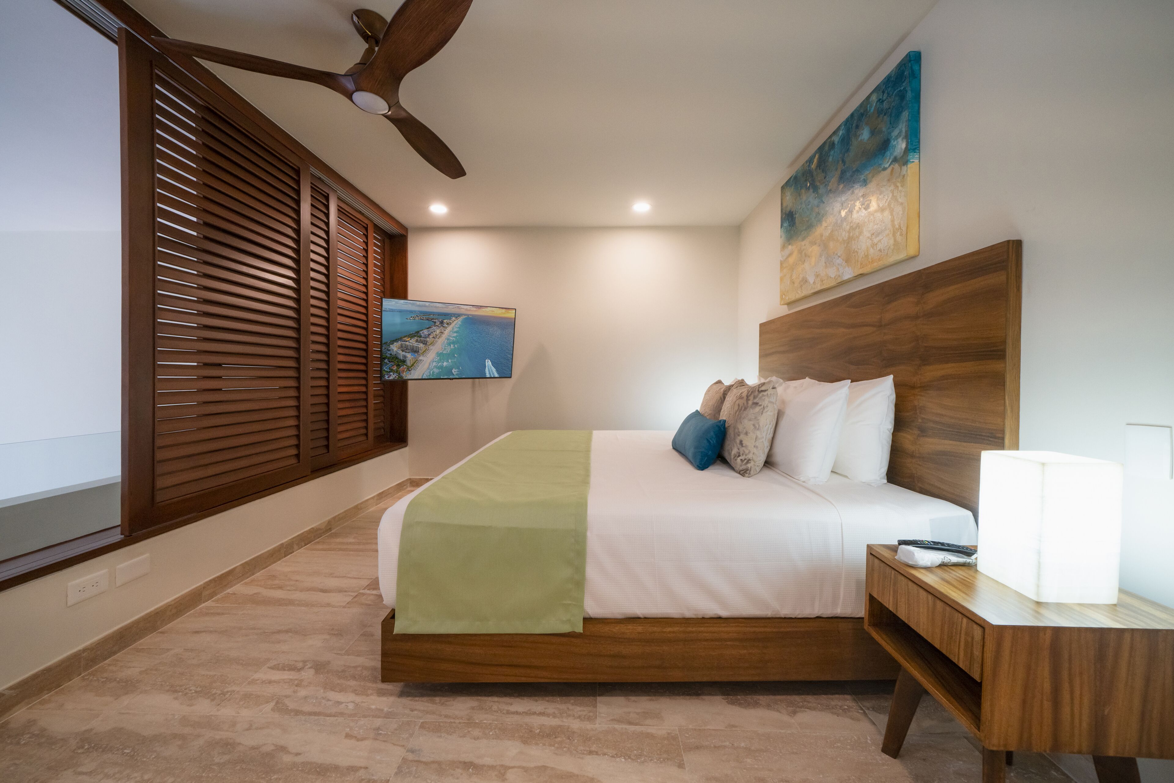 A bedroom with a bed, wooden headboard, bedside table, and a ceiling fan.