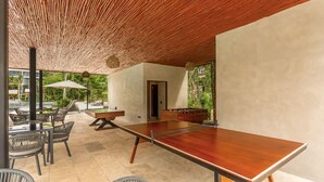 A spacious indoor area with a ping pong table, lounge chairs, and a foosball table. - Awa 107 At AWA Residences - Playacar ll (Playa del Carmen)