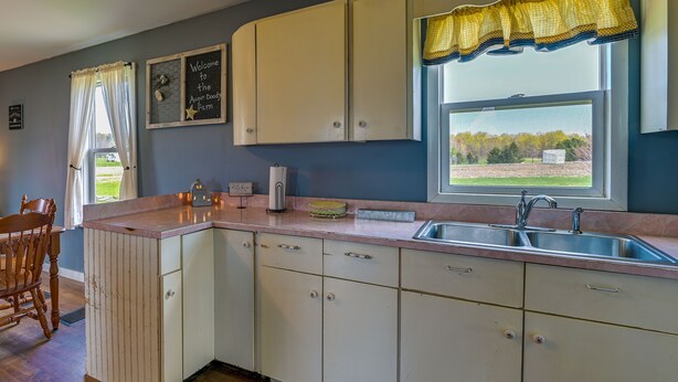 A kitchen with white cabinets, a sink, and a window with a view of the outdoors. - Upstate New York Vacation Rental Near Cooperstown! (Jordanville)