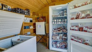 A storage room with shelves stocked with various food items and a refrigerator with open doors displaying packaged meats. - Upstate New York Vacation Rental Near Cooperstown! (Jordanville)