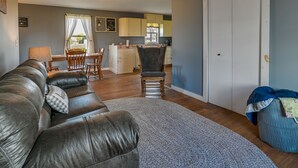 A living room with a leather sofa, a dining table, and a kitchen in the background. - Upstate New York Vacation Rental Near Cooperstown! (Jordanville)