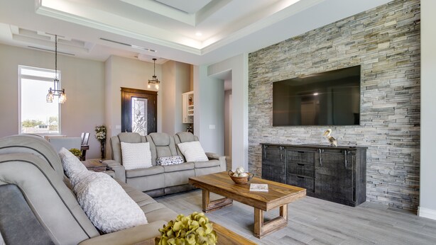 A modern living room with a stone fireplace, a large TV mounted on the wall, and a comfortable seating area with a sofa and a coffee table. - Picturesque Texas Gulf Coast Home in Port Isabel! (Port Isabel)