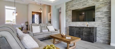 Una sala de estar moderna con chimenea de piedra, un televisor grande montado en la pared y una zona de estar cómoda con sofá y mesa de centro.