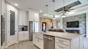 A modern kitchen with white cabinetry, stainless steel appliances, and pendant lighting. - Picturesque Texas Gulf Coast Home in Port Isabel! (Port Isabel)